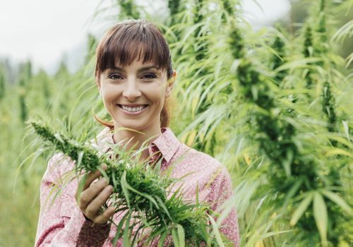 Smiling woman in field of cannabis plants