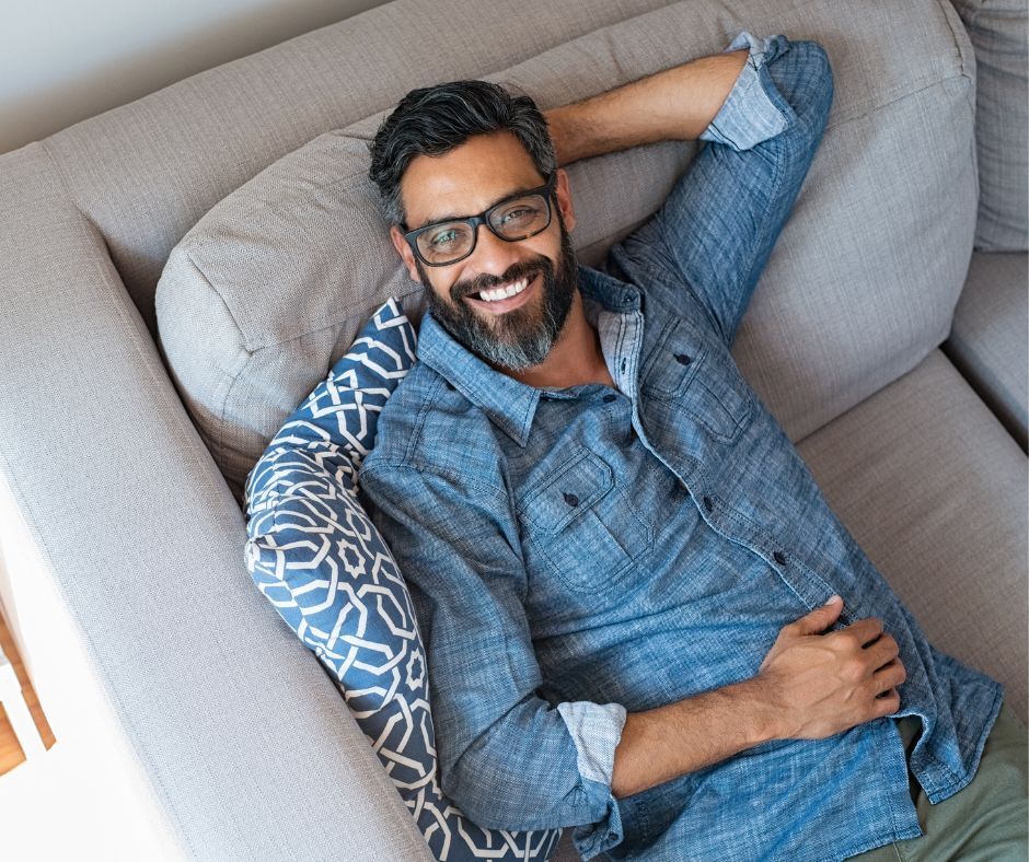 Man laying on couch smiling up at camera