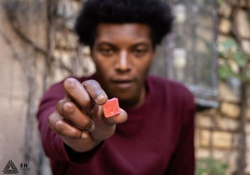 Young man holding a CBD gummy up close to the camera