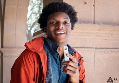 Young man smiling and using a THC-O vape pen